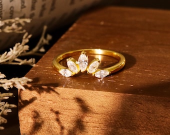 May include: A gold ring with a row of clear marquise-shaped stones set in a curved band.