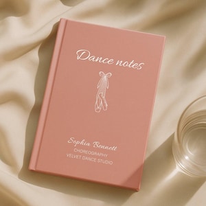 Könnte beinhalten: Ein rosafarbenes Notizbuch mit dem Schriftzug "Dance notes" in Schreibschrift. Unter dem Titel befindet sich eine Zeichnung von Ballettschuhen. Das Notizbuch enthält auch den Namen "Sophia Bennett" und "Velvet Dance Studio".