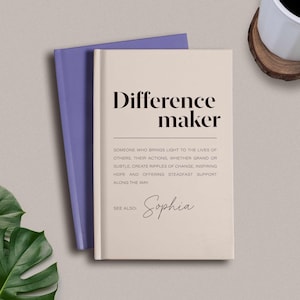 May include: A cream-colored book with the text "Difference maker" in black font. The text below defines a difference maker as someone who brings light to the lives of others. The book also includes the text "See also: Sophia" in black font.