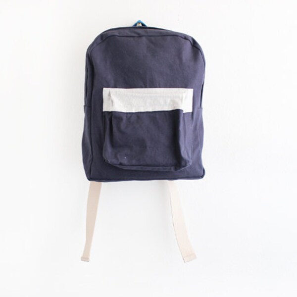 navy canvas backpack with white and grey pouch.