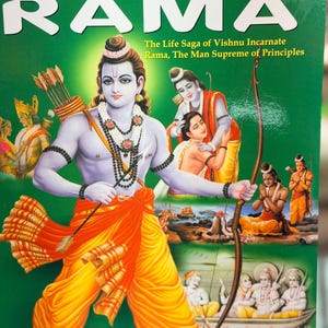 May include: A book cover with the title "The Story of Rama" in large white letters. The cover features a colourful illustration of a figure with a bow and arrow, dressed in yellow and orange clothing, with other figures in the background. The text "The Life Saga of Vishnu Incarnate" is also visible.