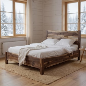 May include: A wooden bed frame with a natural wood headboard and footboard. The bed is made up with white sheets, pillows, and a white blanket. The bed sits on a woven rug in a room with windows.