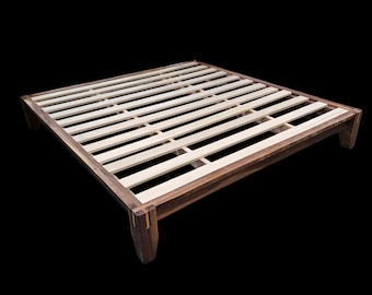 May include: A wooden bed frame with a dark brown finish and a slatted design. The frame has a rectangular shape with four sturdy legs. The bed frame is made of wood and is designed to support a mattress.