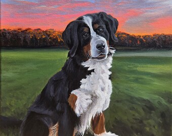 May include: A Bernese Mountain Dog puppy sits in a field of green grass with a pink and blue sunset in the background. The dog is looking directly at the viewer with its right paw raised.