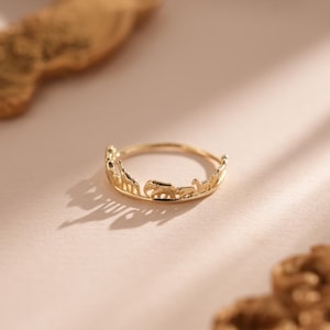 May include: A gold ring featuring a design of animals, including a giraffe, elephant, and other safari animals.