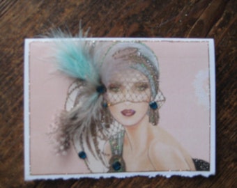 May include: A vintage-style illustration of a woman wearing a blue feather hat with a veil and sparkling jewels. The woman has dark hair and is wearing a light pink dress.