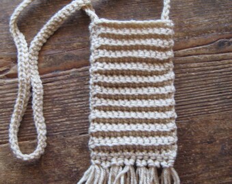 May include: A crocheted beige bag with a long strap and fringe. The bag is made of a soft, textured yarn and has a simple, classic design.
