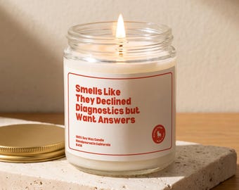 May include: A clear glass jar candle with a lit wick and white wax. The label features a red border and red text that reads: Smells Like They Declined Diagnostics but Want Answers. It also states 100% Soy Wax Candle Handpoured in California.