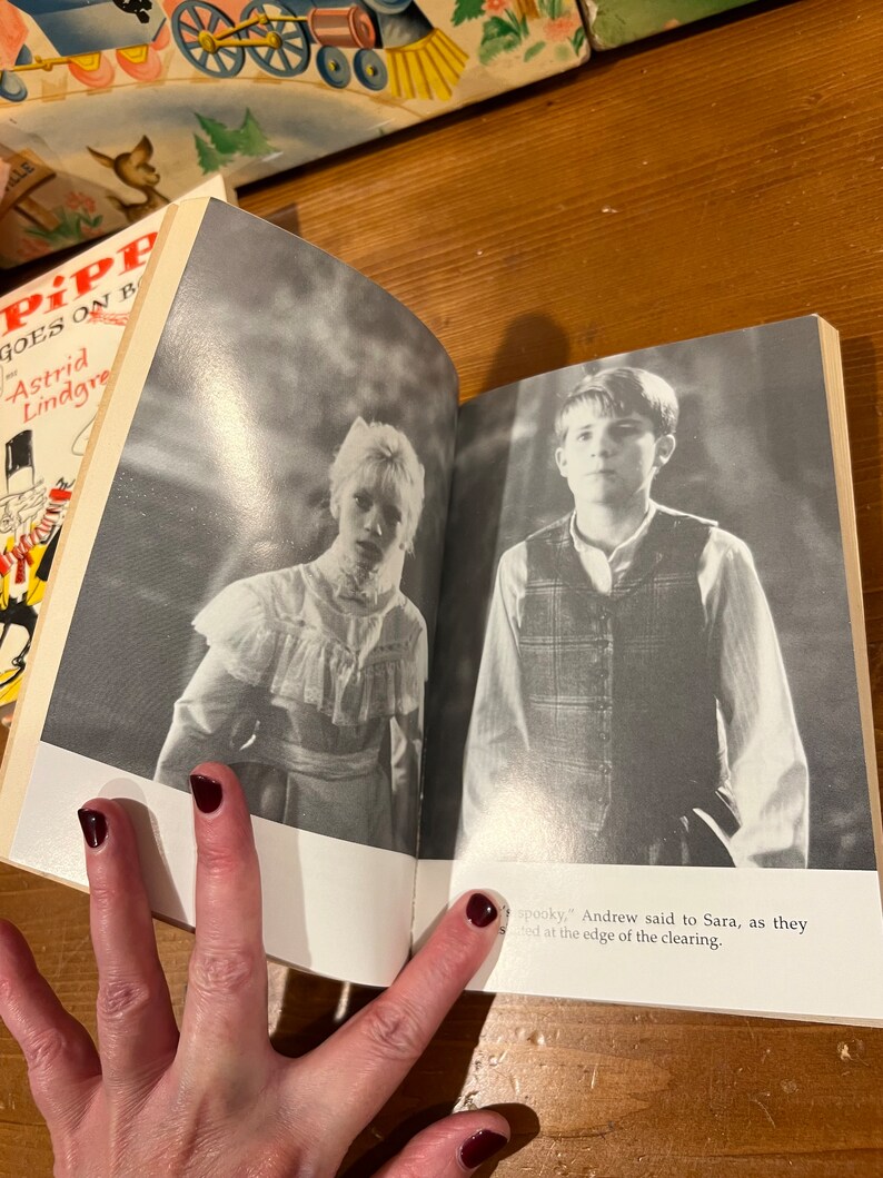 May include: An open book with a black and white photo of a young girl on the left page and a young boy on the right page. The text on the right page reads "spooky," Andrew said to Sara, as they stood at the edge of the clearing."