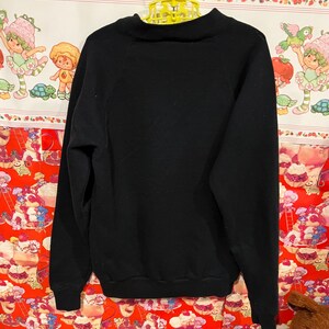 Op de afbeelding: Zwarte longsleeve met een mock neck en raglan mouwen.