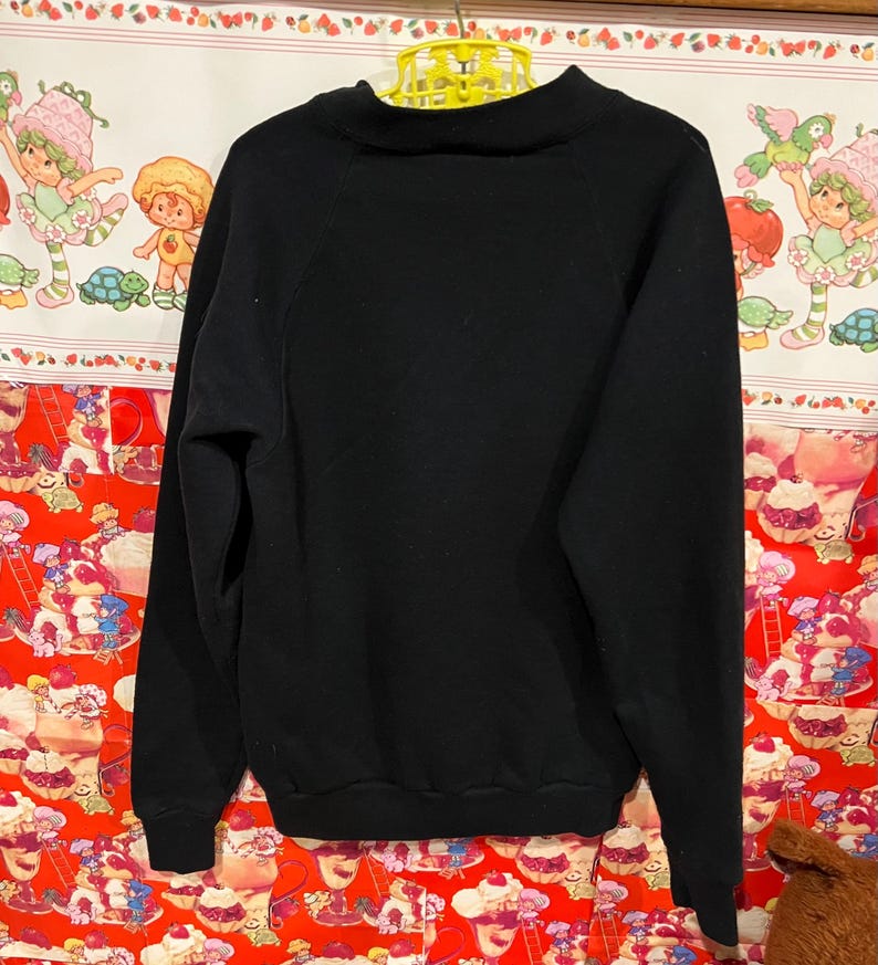 Op de afbeelding: Zwarte longsleeve met een mock neck en raglan mouwen.