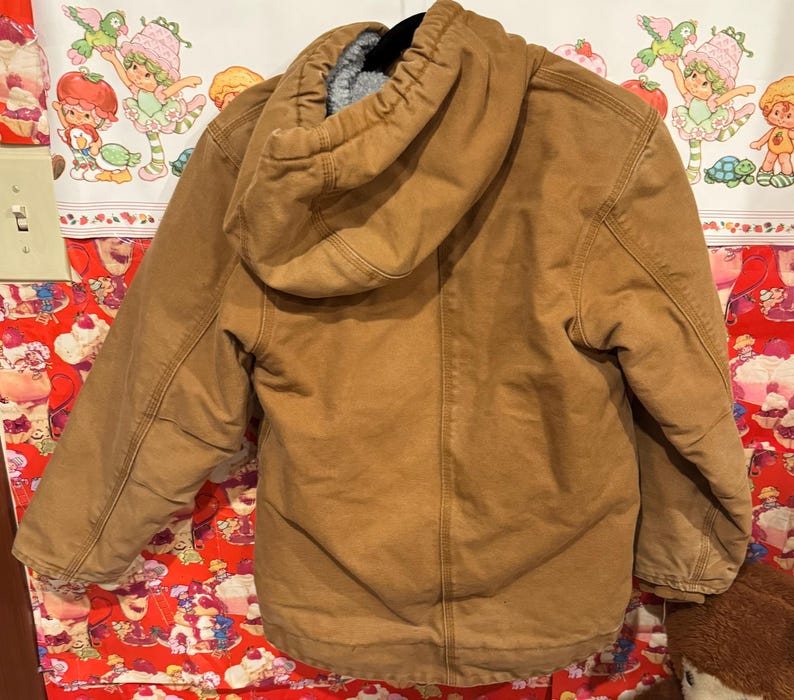 Puede incluir: Chaqueta con capucha marr&oacute;n con forro polar gris. La chaqueta tiene cierre de cremallera completo y m&uacute;ltiples bolsillos. La capucha es grande y est&aacute; forrada con el mismo material de forro polar gris. La chaqueta est&aacute; hecha de tela duradera estilo workwear.