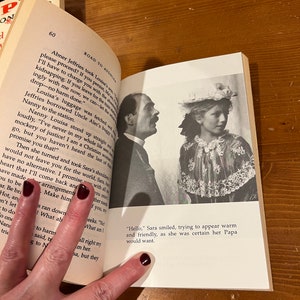 May include: A vintage book open to a page with a black and white photo of a man and a young girl. The book is titled "Road to Avonlea". The text on the page reads "Abner Jeffries took Louisa's arm. "I'll have to charge you with the serious offense of kidnapping. If you leave for the train willingly with me now, we can let the whole thing drop - no harm done."