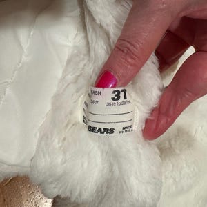 May include: Close-up of a white, fluffy garment with a label that reads "31" and "35 1/2 to 38 ins." The label also includes the brand name "SEARS" and "MADE IN U.S.A."