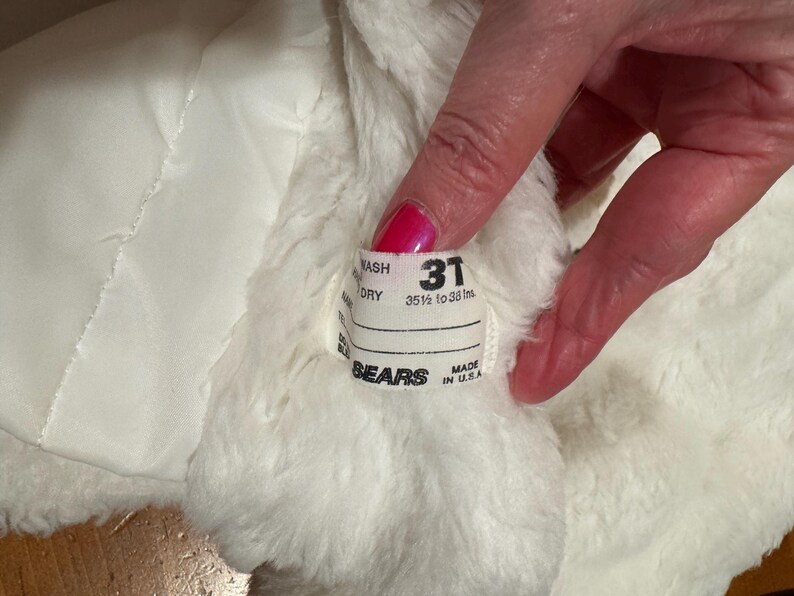 May include: Close-up of a white, fluffy garment with a label that reads "31" and "35 1/2 to 38 ins." The label also includes the brand name "SEARS" and "MADE IN U.S.A."