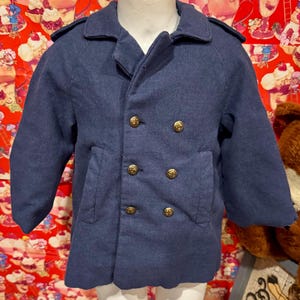 May include: A navy blue double-breasted coat with gold-colored buttons. The coat has a classic design with a collar and two front pockets. The coat is made of a soft, textured fabric.