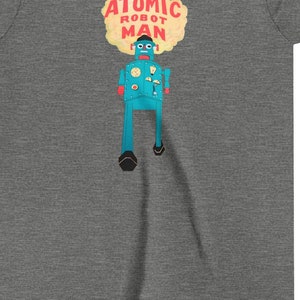 Könnte beinhalten: Ein graues T-Shirt für Jugendliche mit einem blauen Roboter-Motiv und dem Text "ATOMIC ROBOT MAN" in einer gelben Wolke.