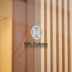 May include: A logo for "MR. FUSION HOME ENERGY REACTOR" is displayed on a glass surface. The logo is a grey circle with a white design. The background features vertical wooden panels.
