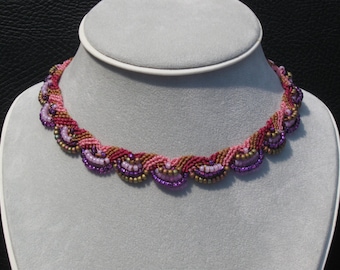 May include: A pink, purple, and gold beaded necklace with a scalloped design. The necklace is on a white mannequin bust.