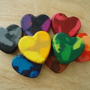 Puede incluir: Una colecci&oacute;n de ceras en forma de coraz&oacute;n en varios colores, incluyendo rojo, verde, amarillo y azul. Las ceras est&aacute;n dispuestas sobre una superficie de madera clara, mostrando sus vibrantes tonos y formas &uacute;nicas.