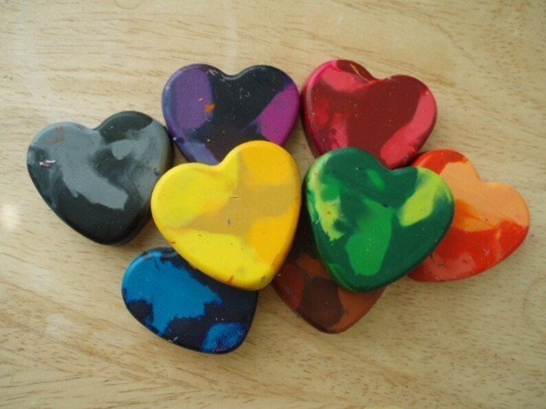 Puede incluir: Una colecci&oacute;n de ceras en forma de coraz&oacute;n en varios colores, incluyendo rojo, verde, amarillo y azul. Las ceras est&aacute;n dispuestas sobre una superficie de madera clara, mostrando sus vibrantes tonos y formas &uacute;nicas.