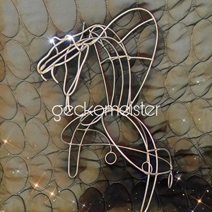 May include: A silver wire sculpture of a stylized horse with a curved neck and a long tail. The sculpture is on a brown background with a pattern of circles.