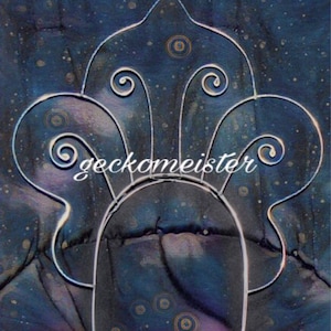 May include: A silver wire headpiece with a stylised design of a crown with swirls. The headpiece is on a blue and purple background with white speckles.