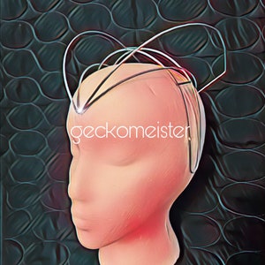 Può includere: Un cerchietto per capelli in filo d'argento con più anelli e curve. Il cerchietto è indossato su una testa di manichino. Il cerchietto è su uno sfondo scuro con un motivo di cerchi.