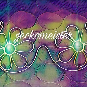 Op de afbeelding: Een paar draad bloemen-vormige bh-achtige objecten met een groene en blauwe achtergrond. Het woord "gecko meister" is in het wit in het midden van de afbeelding geschreven.