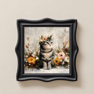Puede incluir: Pintura enmarcada de un gato atigrado gris con una corona floral, rodeado de flores coloridas. La obra de arte est&aacute; sobre un fondo suave y texturizado. El marco negro tiene un borde decorativo y ondulado.