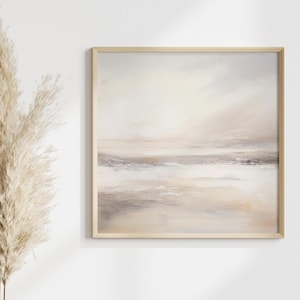 Puede incluir: Pintura abstracta de paisaje en un marco de madera cuadrado. La obra utiliza una paleta de beige suave, gris y blanco, creando una atmósfera tranquila. La pintura representa una escena serena, con un marco de madera clara.