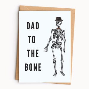 May include: A white greeting card with black text that reads DAD TO THE BONE. The card features a black and white illustration of a human skeleton wearing a black bowler hat and a brown bow tie, positioned next to a brown paper envelope.