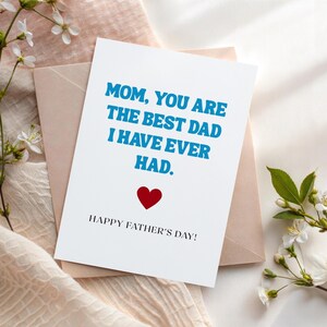 May include: A white Father's Day card with blue text that reads "MOM, YOU ARE THE BEST DAD I HAVE EVER HAD." A red heart is below the text, and "HAPPY FATHER'S DAY!" is written at the bottom. The card is on a pink envelope.