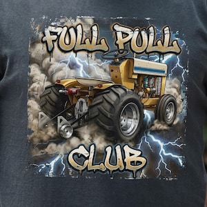 May include: A charcoal gray short-sleeve t-shirt featuring a graphic print of a yellow tractor pulling a load amidst dust and blue lightning. The text "FULL PULL CLUB" is printed in a stylized, graffiti-inspired font above and below the tractor.