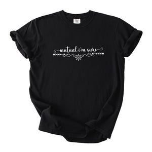 Puede incluir: Una camiseta negra de manga corta con el texto blanco "mutual i'm sure" impreso en el pecho. El texto est&aacute; centrado y flanqueado por adornos blancos decorativos y un peque&ntilde;o icono en forma de copo de nieve debajo de las palabras.