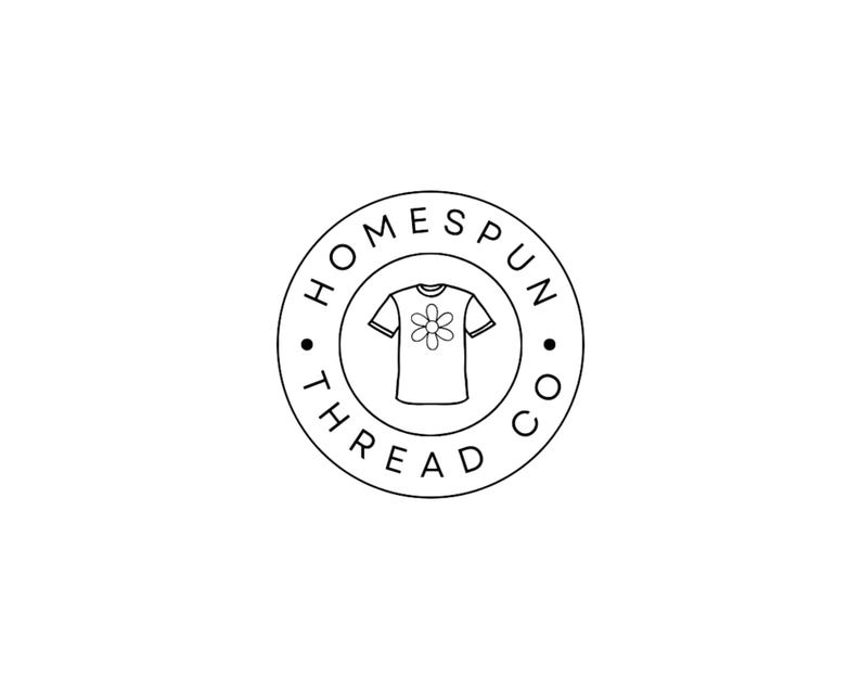 Puede incluir: Un logotipo circular en blanco y negro con el texto HOMESPUN THREAD CO. dispuesto alrededor del borde. En el centro, hay un dibujo lineal sencillo de una camiseta de manga corta con un gr&aacute;fico de una flor en el &aacute;rea del pecho.