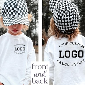 May include: A white long-sleeve sweatshirt featuring a black and white checkered baseball cap. The front of the sweatshirt displays the text YOUR CUSTOM LOGO DESIGN OR TEXT, and the back features the same text in a larger, bold font.