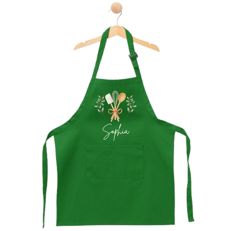 May include: Green kitchen apron with a pocket, featuring a white design of kitchen utensils and the name "Sophia" in white script.