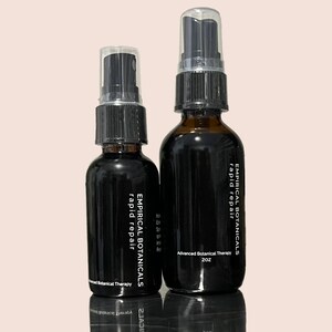 Puede incluir: Dos botellas de vidrio ámbar con tapas de pulverización negras y etiquetas que dicen "Empirical Botanicals rapid repair" y "Advanced Botanical Therapy 2 oz".