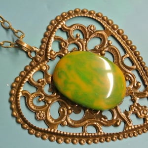 Collar colgante con genuina cosecha probada de la década de 1950 amarillo escamoso / verde hierba probada cabujón de plástico de baquelita y corazón de bronce de color antiguo