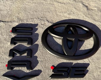 Nakładki na emblematy Toyota Camry SE 2018–2024 • Osłona emblematu Camry Blackout • Akcesoria samochodowe • Toyota PT948-03191-02