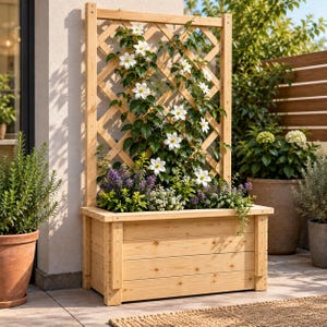 Op de afbeelding: Een rechthoekige plantenbak van lichtgekleurd hout met een bevestigd verticaal latwerk. De plantenbak bevat een klimplant met witte bloemen en groene bladeren, samen met kleinere paarse en witte bloeiende planten aan de basis.