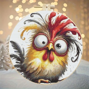 May include: A cross-stitch hoop featuring a whimsical cartoon rooster with large, expressive eyes. The rooster has a red comb, yellow and black feathers, and a red wattle. The background is a soft, blurred bokeh effect.