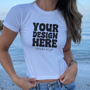 May include: White cropped t-shirt with the text "YOUR DESIGN HERE" in black, retro-style lettering. The text "mocks to go" is printed below in smaller font.