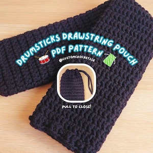 May include: Black crochet drawstring pouch for holding drumsticks. The pouch is closed by pulling on the drawstring. The image includes the text "Drumsticks Drawstring Pouch PDF Pattern @customcrochetissg Pull to Close!"