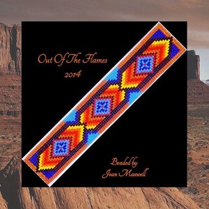 May include: A beaded Native American style bracelet with a geometric pattern in shades of orange, yellow, blue, and black. The bracelet is titled "Out Of The Flames 2014" and is beaded by Joan Maxwell.