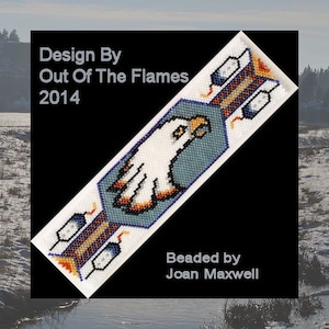 Könnte beinhalten: Perlenarmband mit einem weißen Adler-Design auf blauem Hintergrund. Das Armband hat orange, blaue und weiße Akzente. Der Text "Design By Out Of The Flames 2014" und "Beaded by Joan Maxwell" ist auf dem Bild.