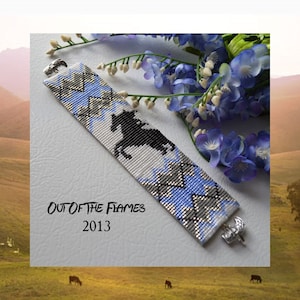 May include: A beaded bracelet with a black and white horse design on a white background with blue and silver accents. The bracelet has silver clasps and the text "OUT OF THE FLAMES 2013" is printed below the bracelet.