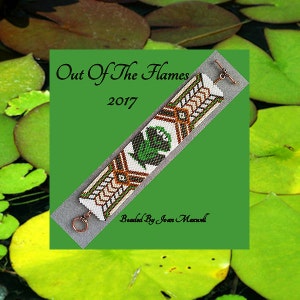 May include: A beaded bracelet featuring a geometric design in green, white, brown and black. The bracelet has a copper clasp and the text "Out Of The Flames 2017 Beaded By Joan Maxwell" is printed on the background.