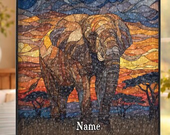 Könnte beinhalten: Glasbild mit einem Elefanten vor einem Sonnenuntergang. Das Kunstwerk verwendet warme Farben wie Orange, Gelb und Braun, mit blauem Himmel. Das Wort "Name" steht unten. Das Bild ist schwarz gerahmt und hängt an einer Kette.